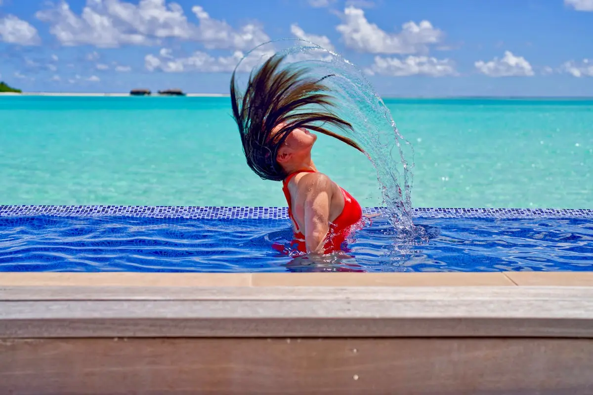 A woman in a red swimsuit splashing in the water