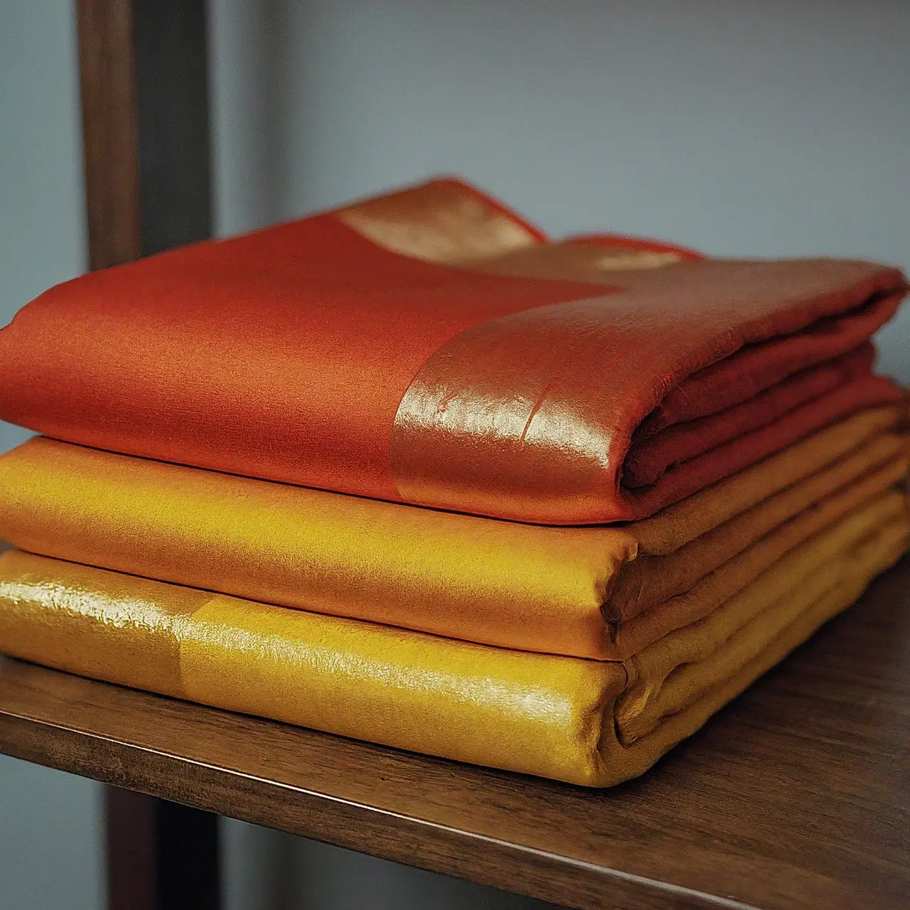 A neatly folded silk saree displayed on a wooden shelf. 35mm stock photo