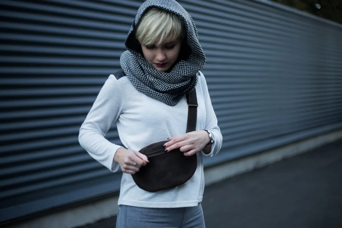 young woman opening her sling bag on the street