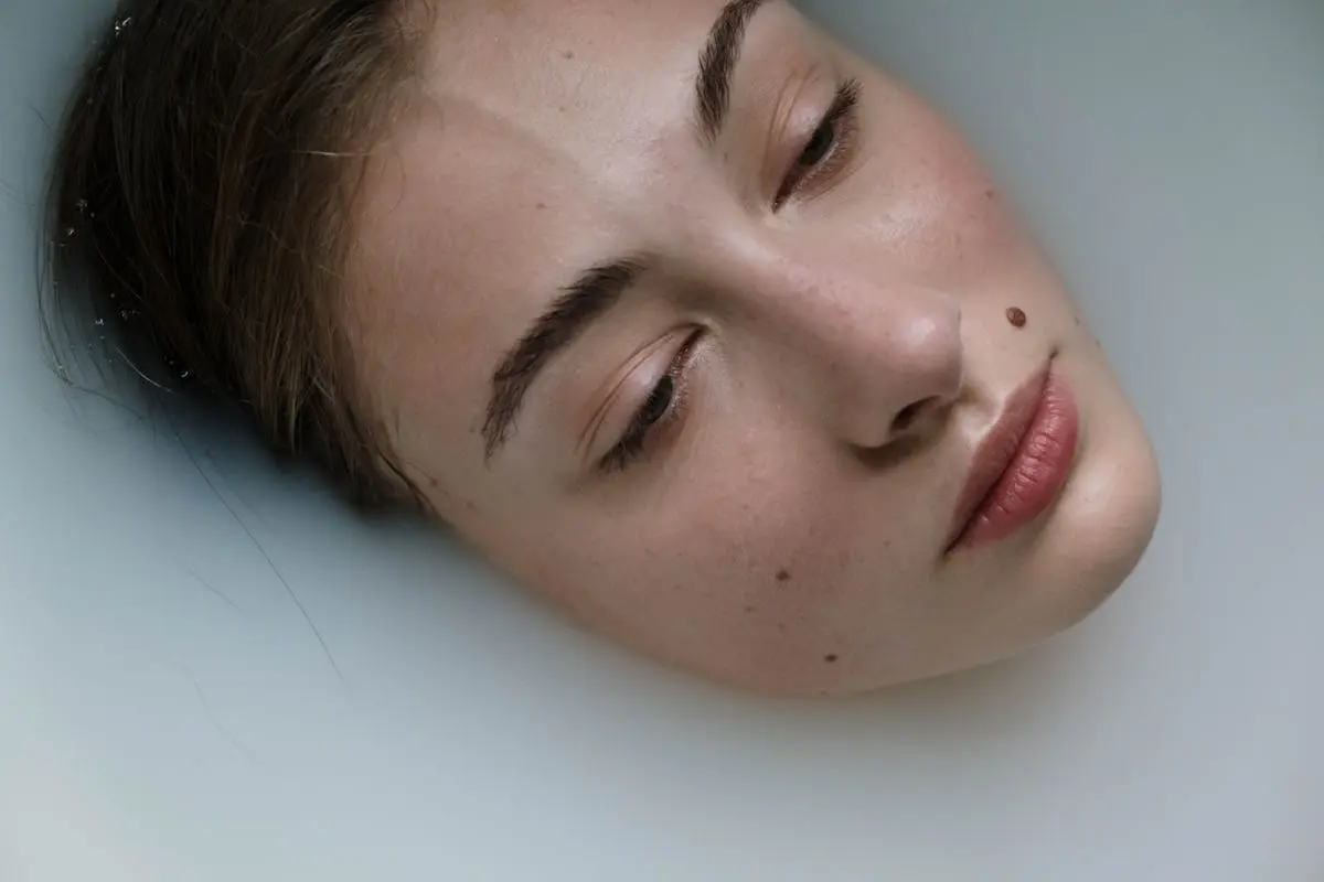 Close-up of a woman relaxing in a milk bath, meditative and serene facial expression.