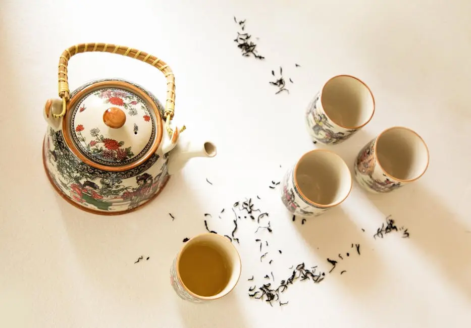 Beautifully designed teapot and cups with loose leaf tea on a light surface, creating a serene tea setting.