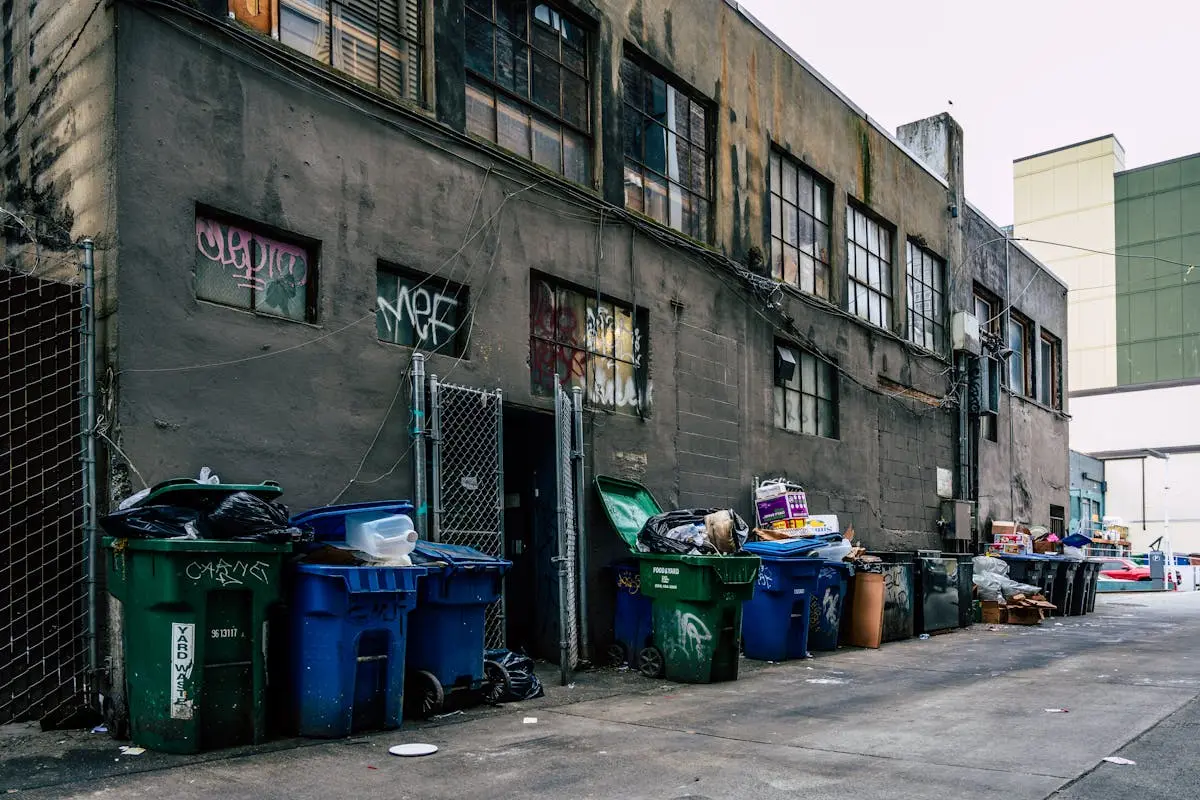 Pavement by Old Dirty Building with Garbage Bins