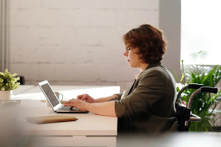 Confident businesswoman working on a laptop in a wheelchair, showcasing remote work capabilities.