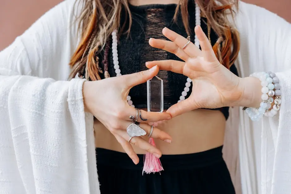 A woman wearing jewelry holds a clear healing crystal, symbolizing spiritual wellness.