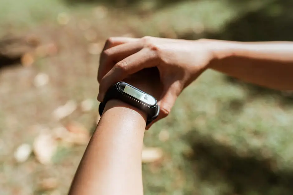 Crop unrecognizable female checking notifications on hand fitness tracker while exercising on green lawn on sunny summer day