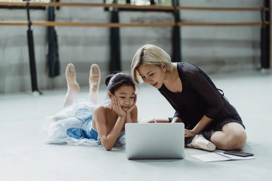 Asian girl with personal instructor using laptop in ballet studio