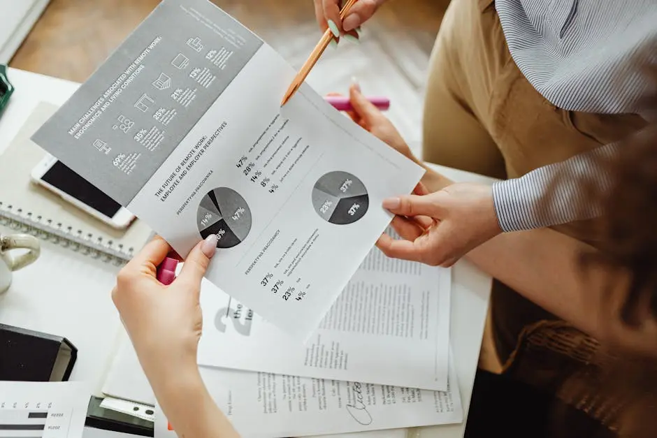 Two people reviewing financial reports and graphs at a desk for analysis and decision-making.