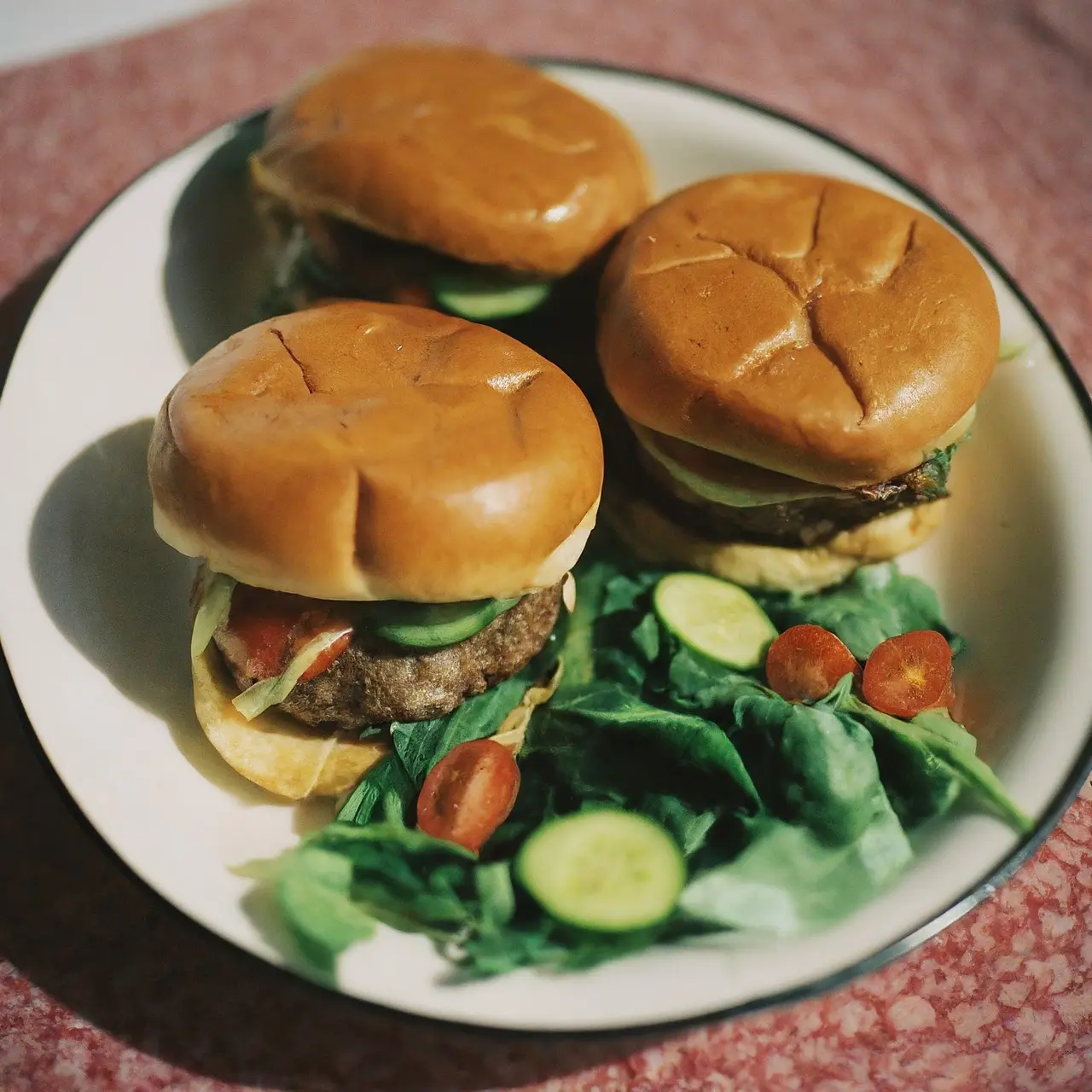 A plate of delicious bison burgers with fresh vegetables. 35mm stock photo