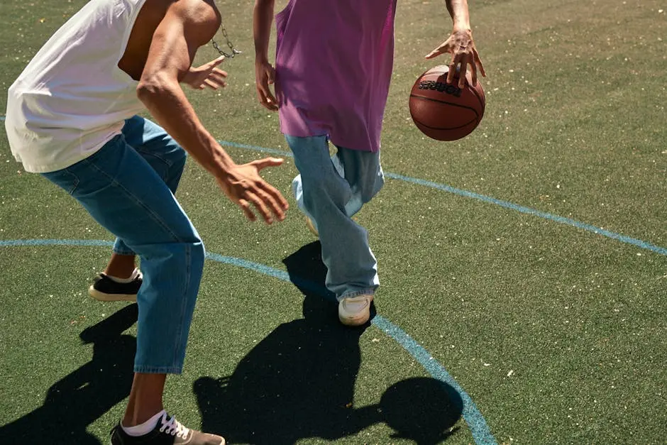 Two men playing basketball on an outdoor court, dribbling and guarding.