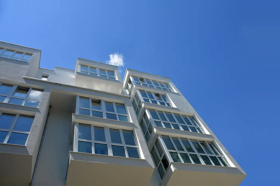 Low angle view of a contemporary apartment building with large glass windows against a clear blue sky.