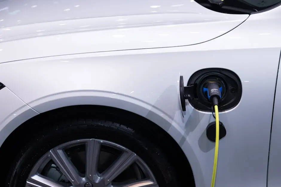 A white electric car is plugged in for charging, close-up view of the charging port.