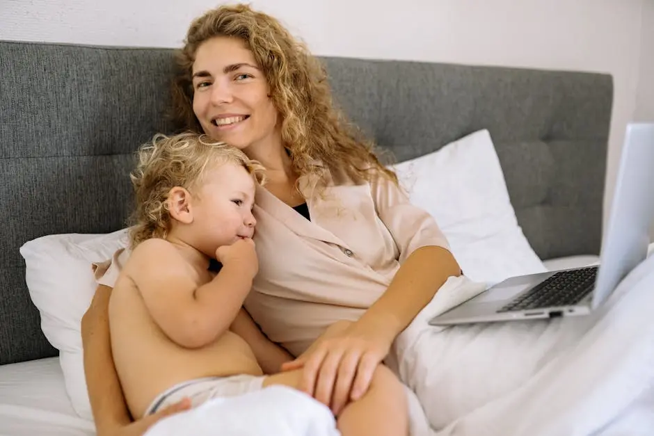 A joyful mother and child relaxing on bed with laptop, capturing family togetherness.