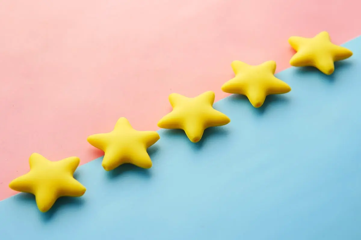 Yellow stars on pink and blue pastel background for rating or review concept.