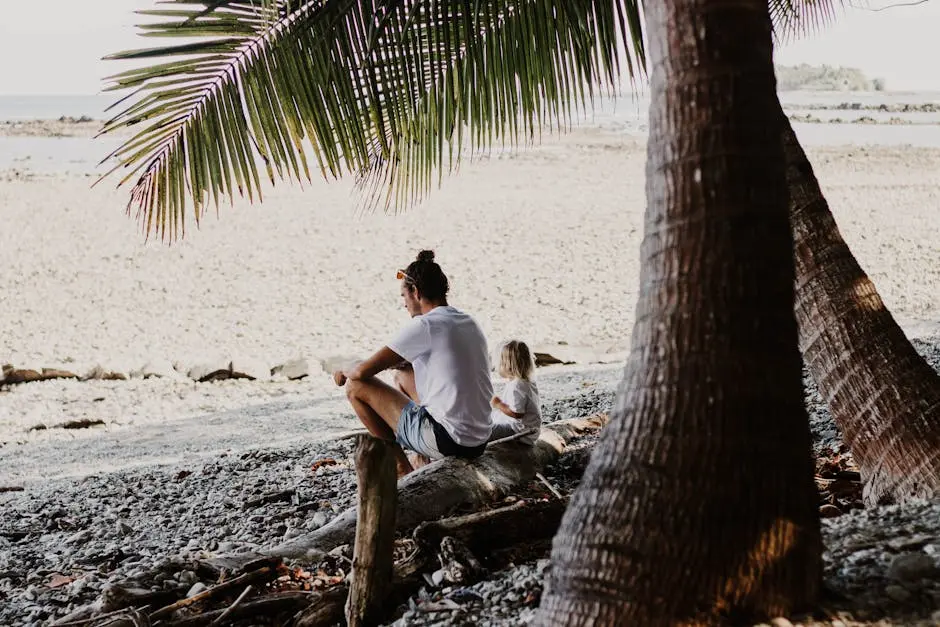 Man and child relax on a serene beach in Costa Rica under palm trees.