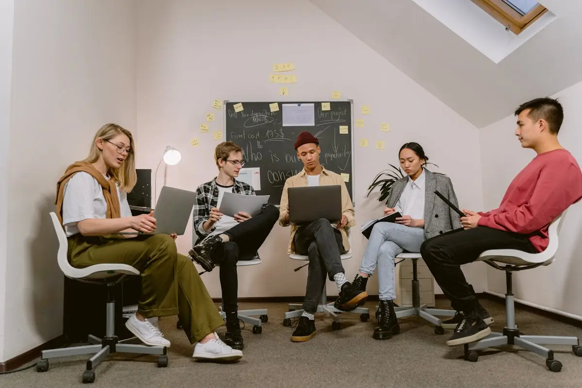 A diverse group of colleagues collaborating in an office meeting, sharing ideas and using laptops.