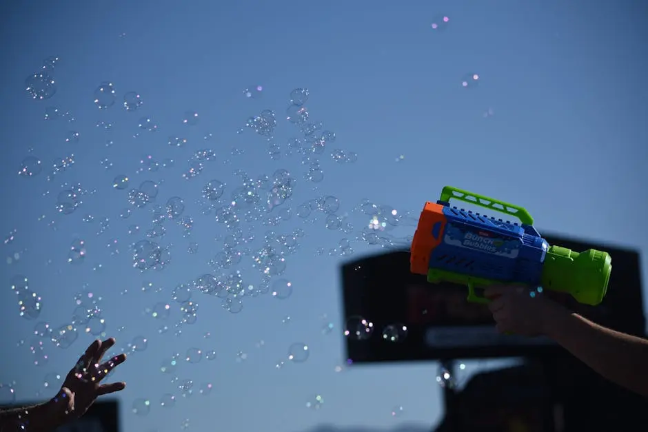 Bubbles shot from a colorful water gun in the clear blue sky, evoking fun and playfulness.