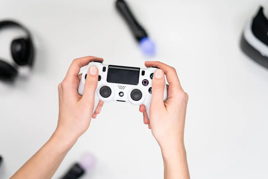 Close-up of hands holding a white game controller on a white background with gaming accessories nearby.