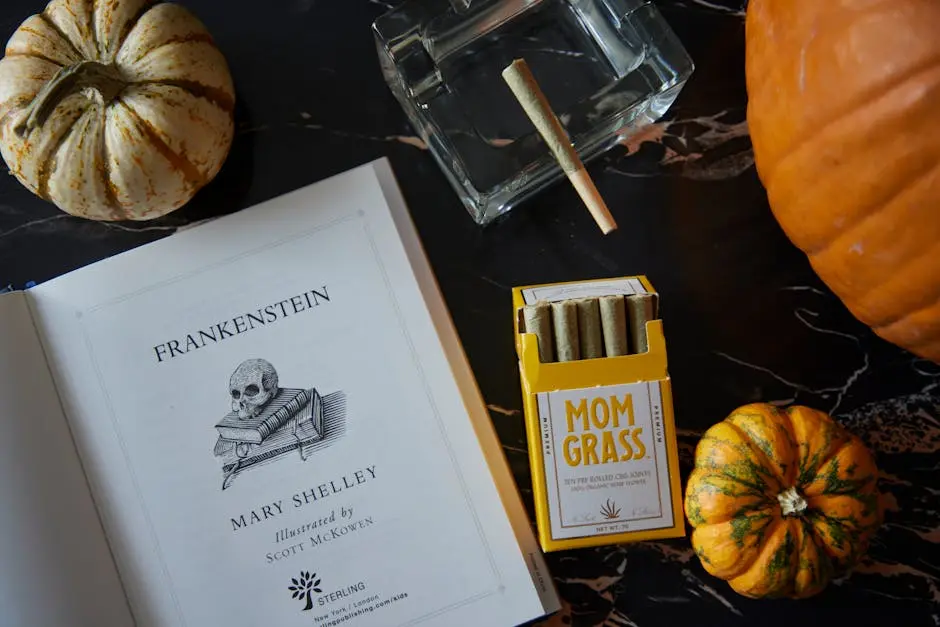 A Halloween-themed flat lay with Frankenstein book, pumpkins, and CBD joints.