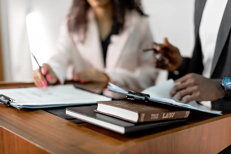 Two lawyers reviewing documents with law books on a desk. Professional legal environment.