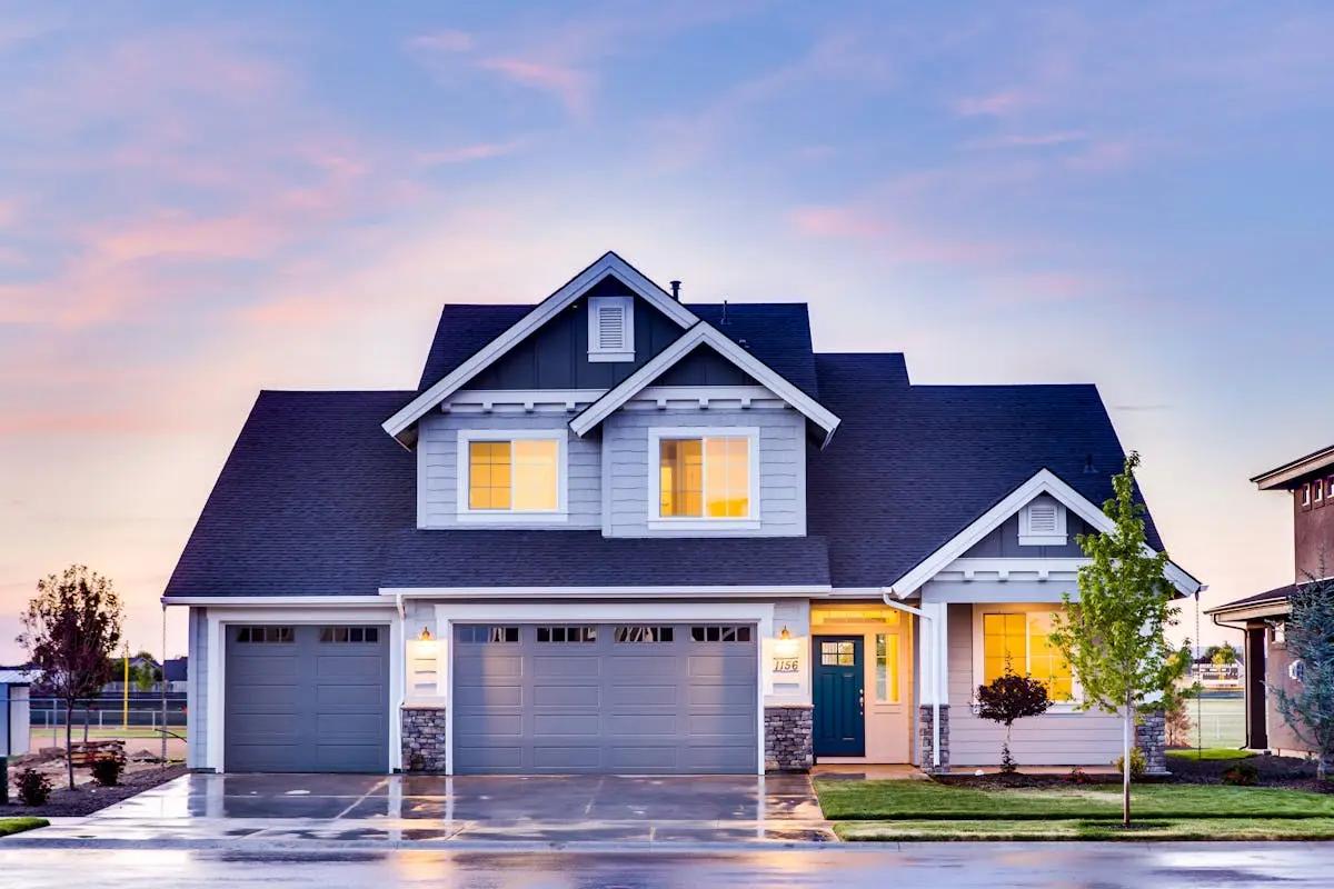 Beautiful two-story house with illuminated windows and garage at dusk.