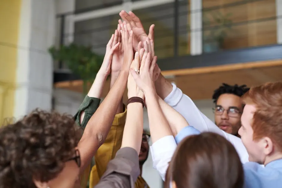 A group of diverse professionals celebrating teamwork with a high-five indoors.