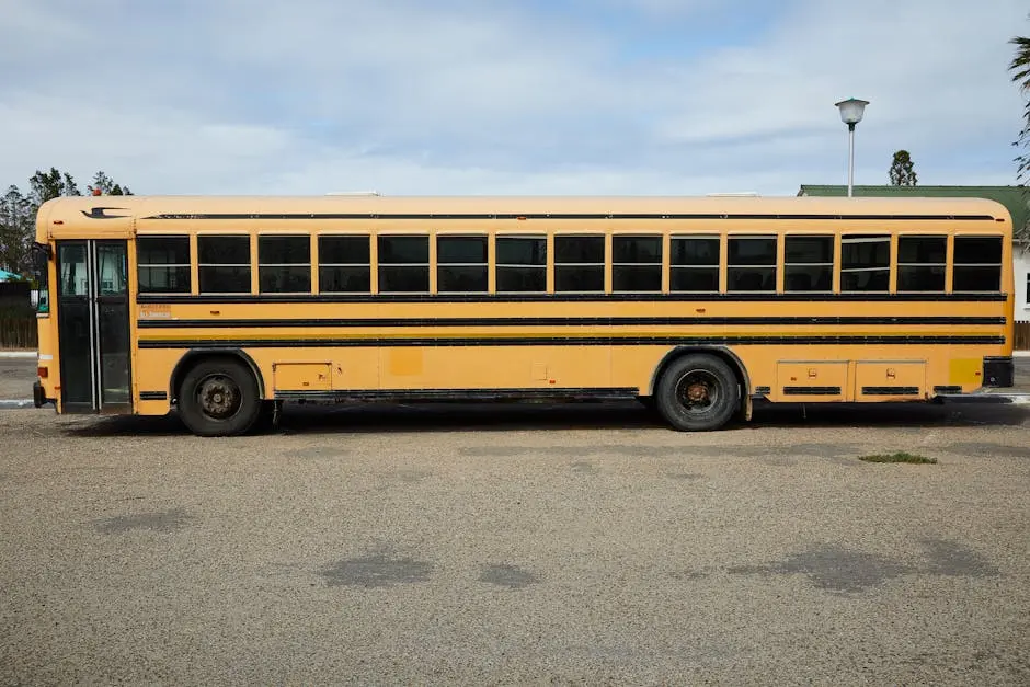 Empty yellow large school bus parked on asphalt road under cloudy blue sky in daytime