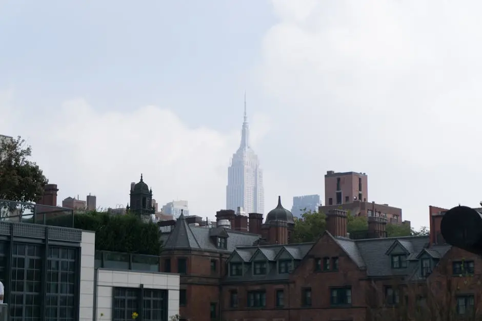 Majestic skyscraper tower in cloud above old buildings in district of New York in daylight