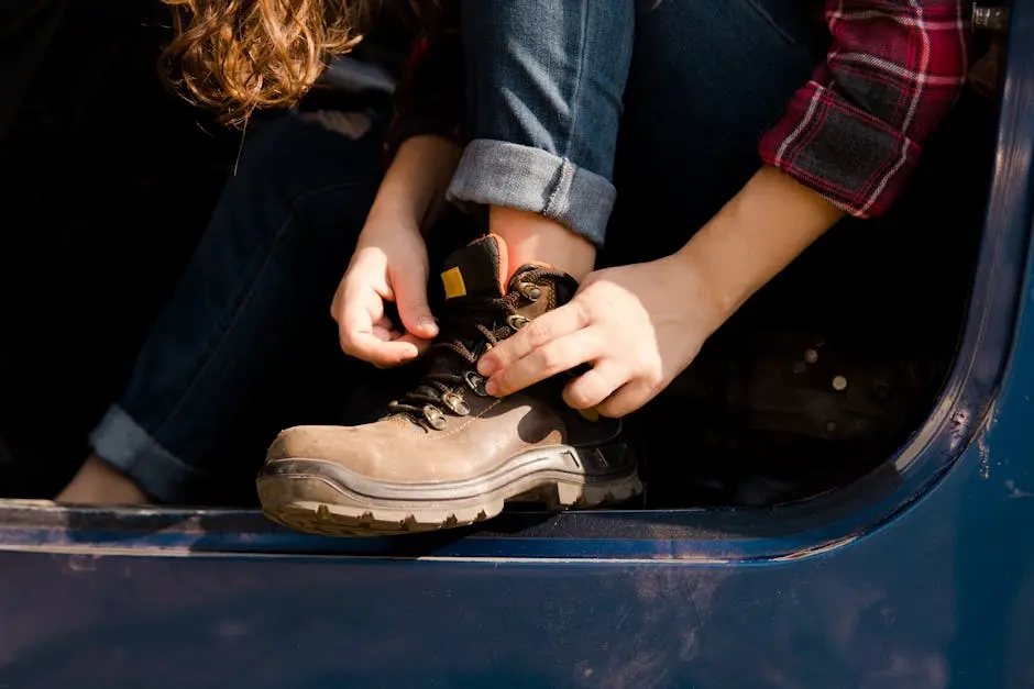 Close-up of woman tying shoelaces on rugged work boots, sitting in a vehicle.