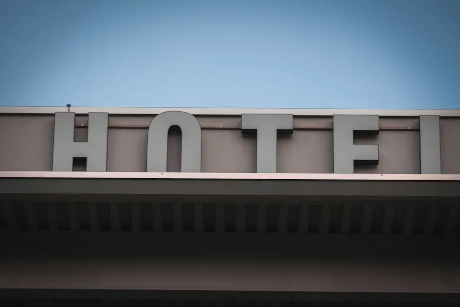 From below fragment of exterior of modern building with Hotel signage against cloudless blue sky in city