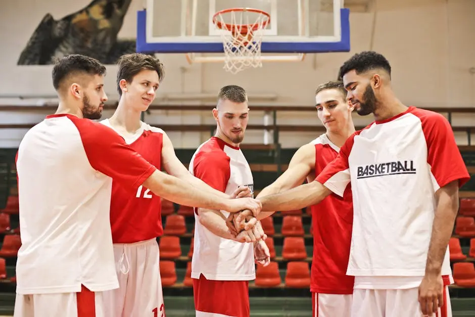 A group of young male basketball players huddle in a gym, ready for practice.