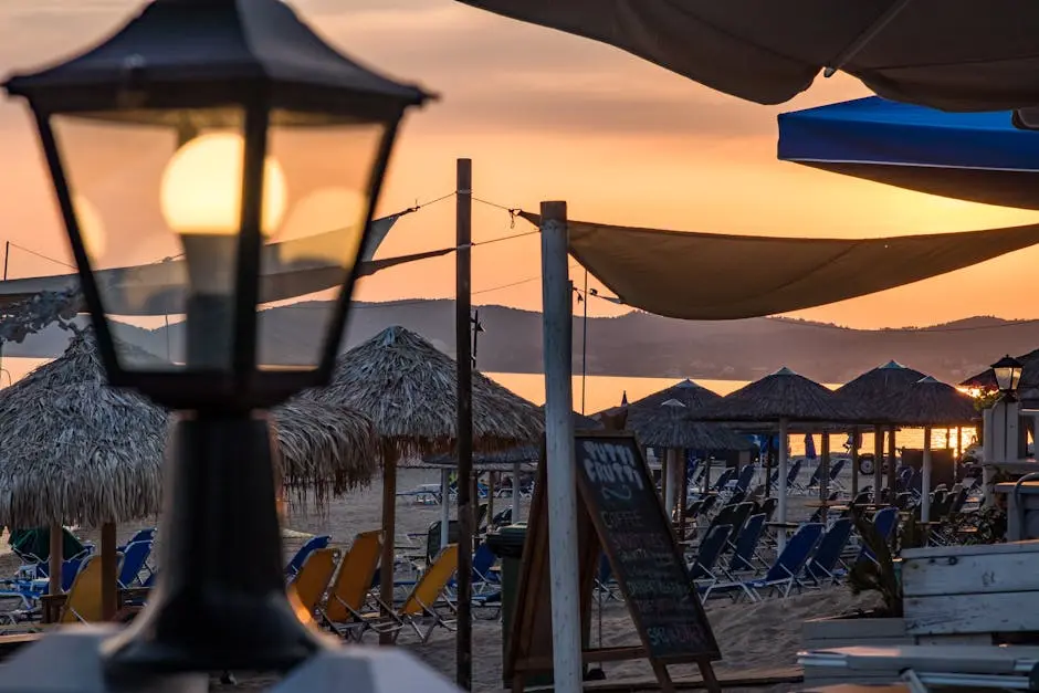 Beachside view at sunset with umbrellas, deck chairs and warm ambient lighting.