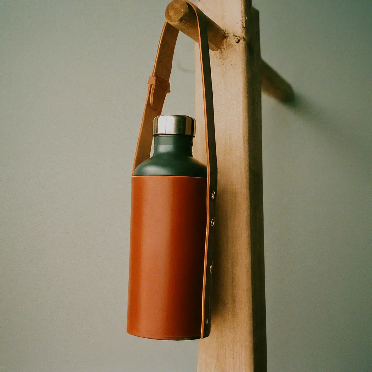 A leather water bottle holder hanging on a wooden peg. 35mm stock photo