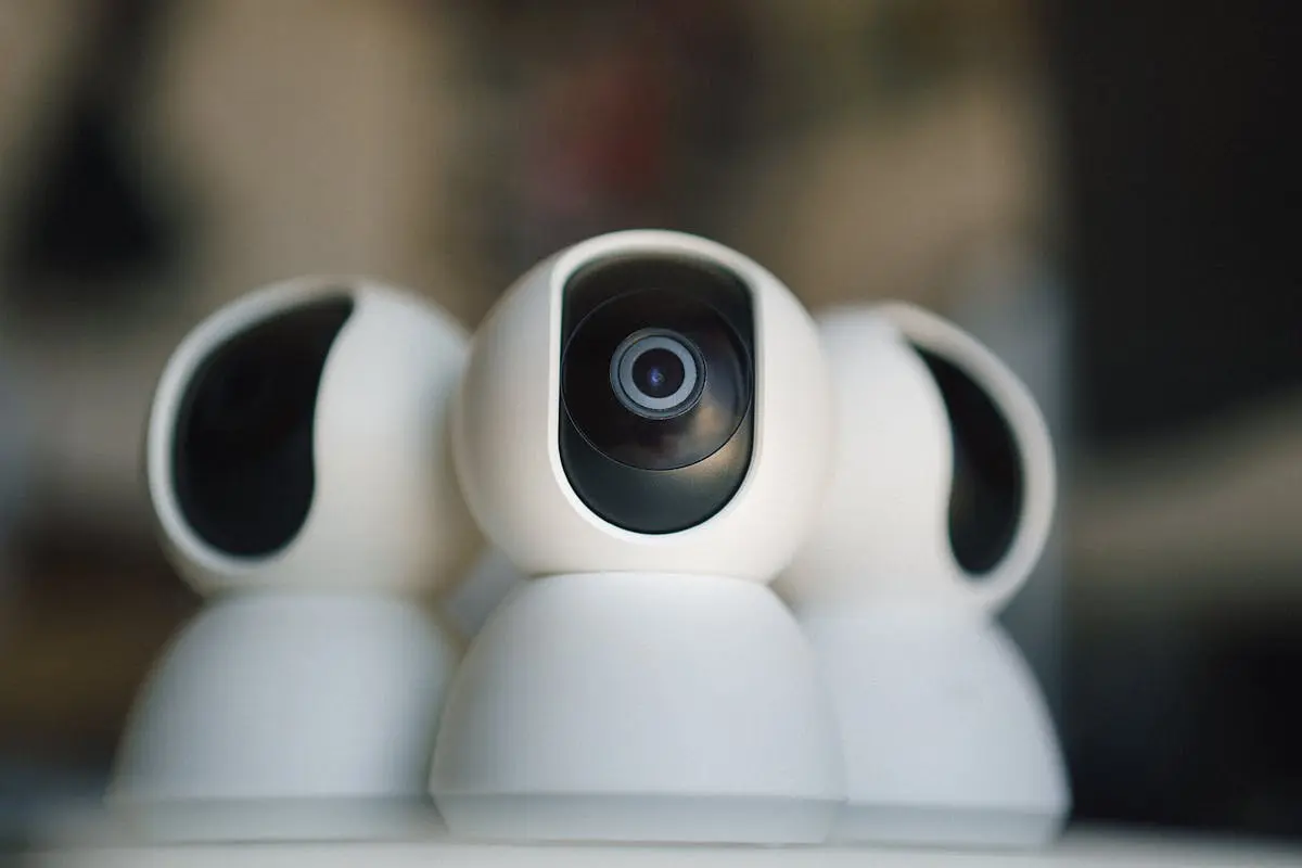 Close-up shot of three white, dome-shaped security cameras with black lenses.