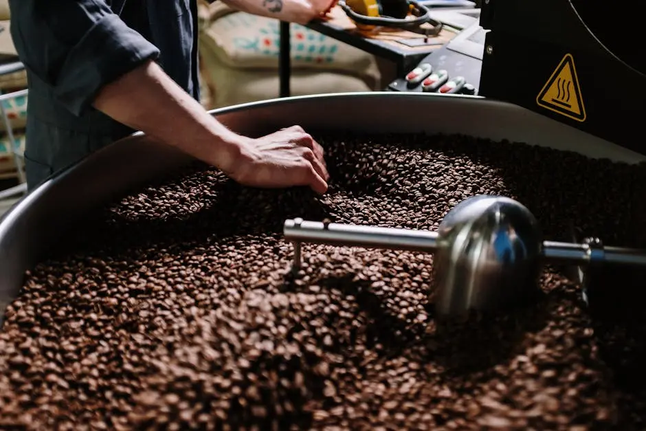 Close-up of a professional roasting coffee beans in an industrial setting, focusing on equipment and beans.