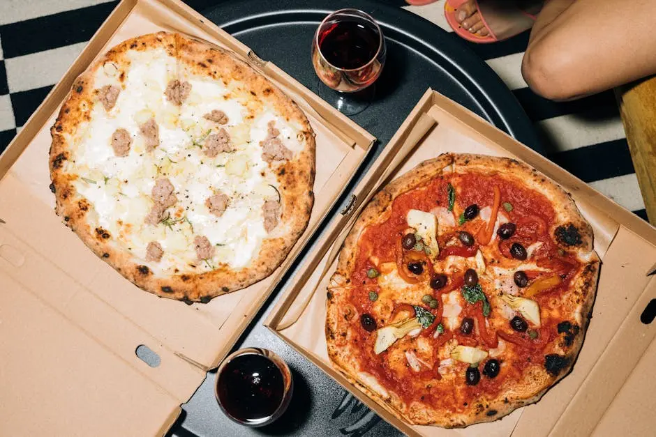 Two pizzas in boxes with glasses of wine, perfect for a cozy meal or pizza party.