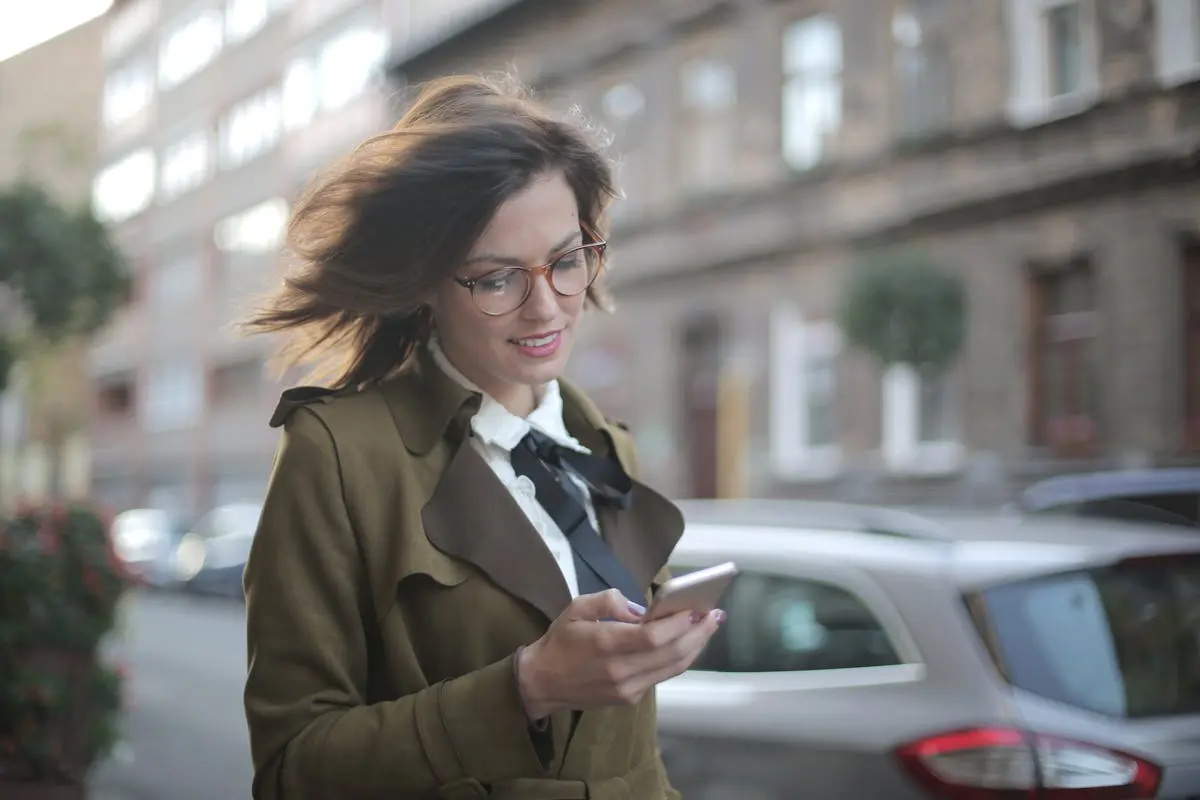 Stylish adult female using smartphone on street