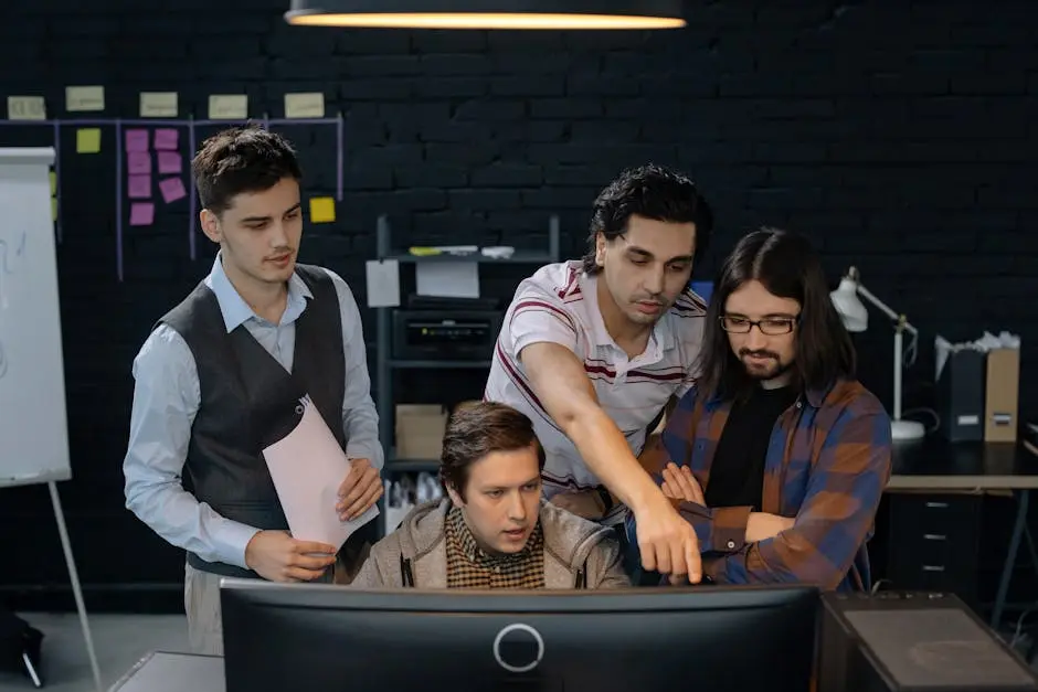 Group of professionals discussing a project at a computer in a modern office environment.