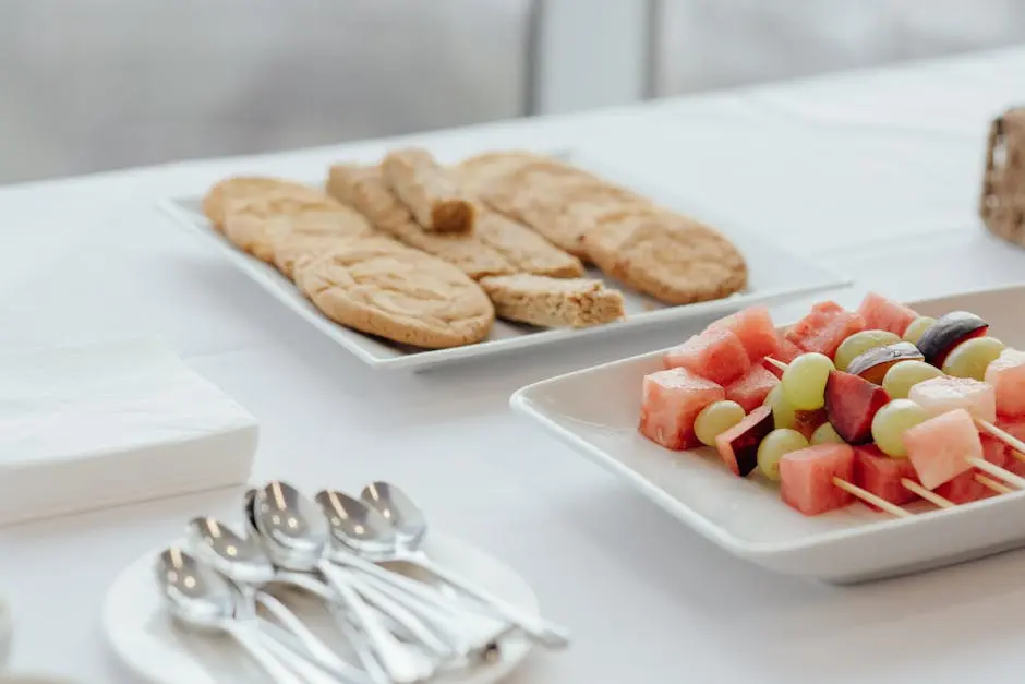 Tasty cookies placed near plate with skewers of fresh watermelon plums and grapes served on table with cutlery in cafe