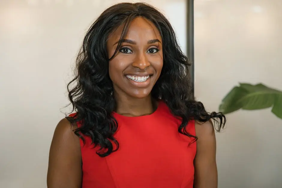 Confident businesswoman smiling in a vibrant red dress, exuding professionalism and positivity.