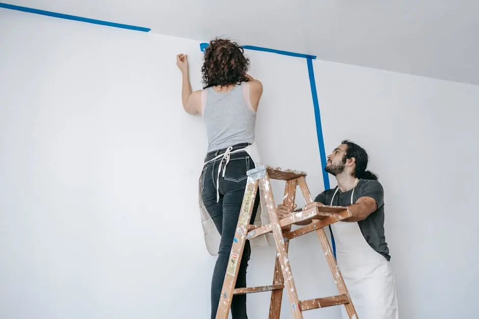 A couple collaborates on home renovation with paint and ladder.