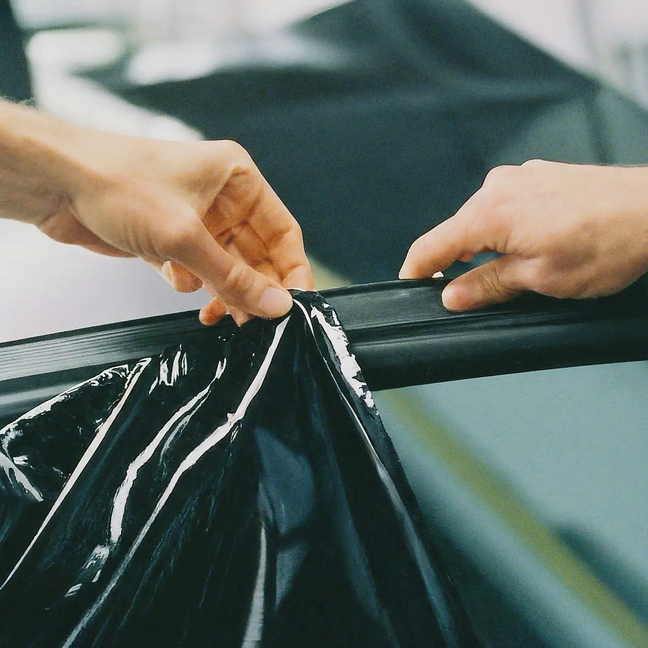 Close-up of hands applying tint on a car window. 35mm stock photo