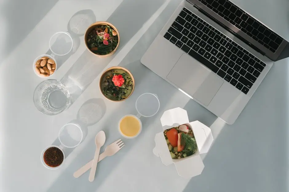 A Laptop Beside Bowls of Healthy Foods on a White Surface