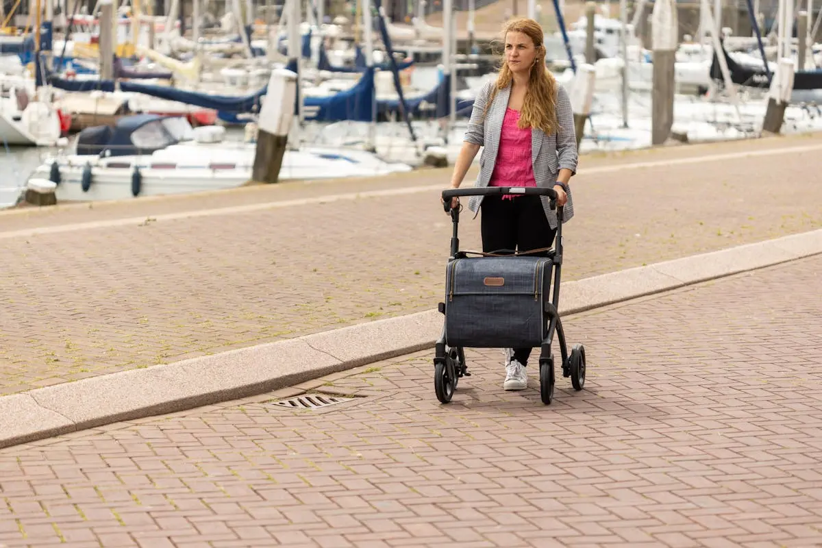 Woman by Marina Pushing Rollator with Shopping Bag