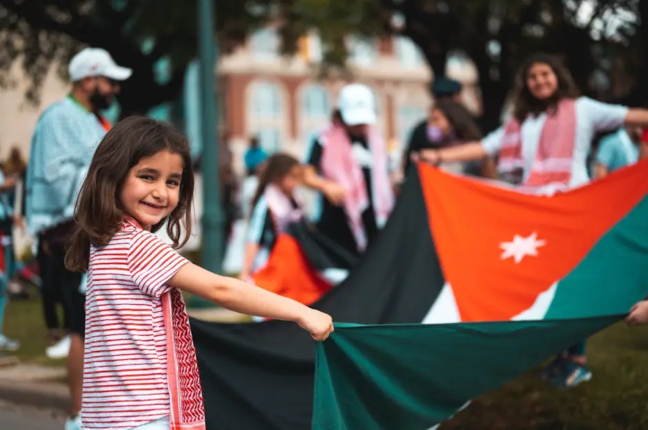 A cheerful girl holds a flag during a lively outdoor protest, celebrating cultural identity.