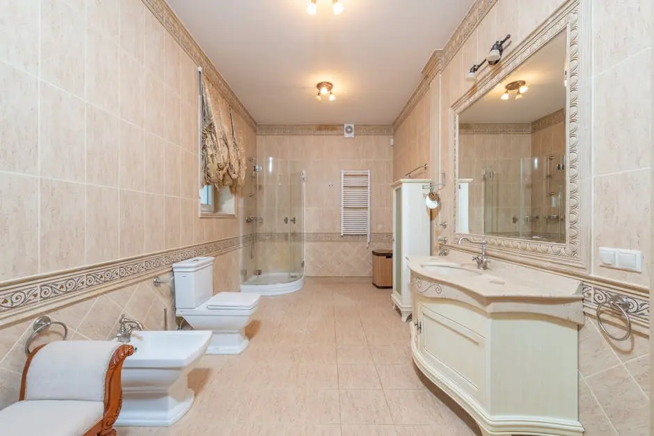 Spacious luxury bathroom featuring beige tiles, elegant furnishings, and modern fixtures.