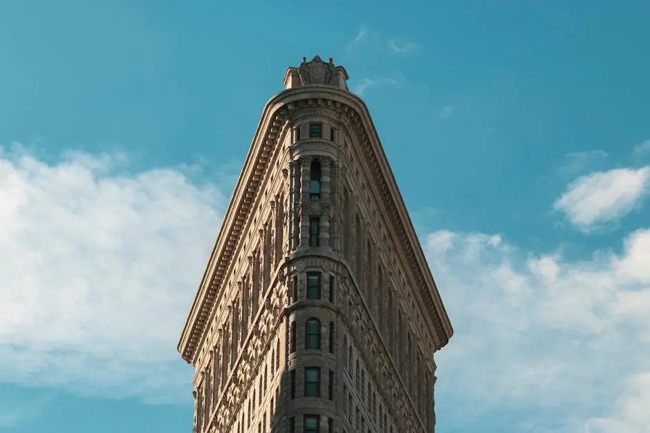 Flatiron Building in New York City under a bright sky, showcasing its unique architecture.