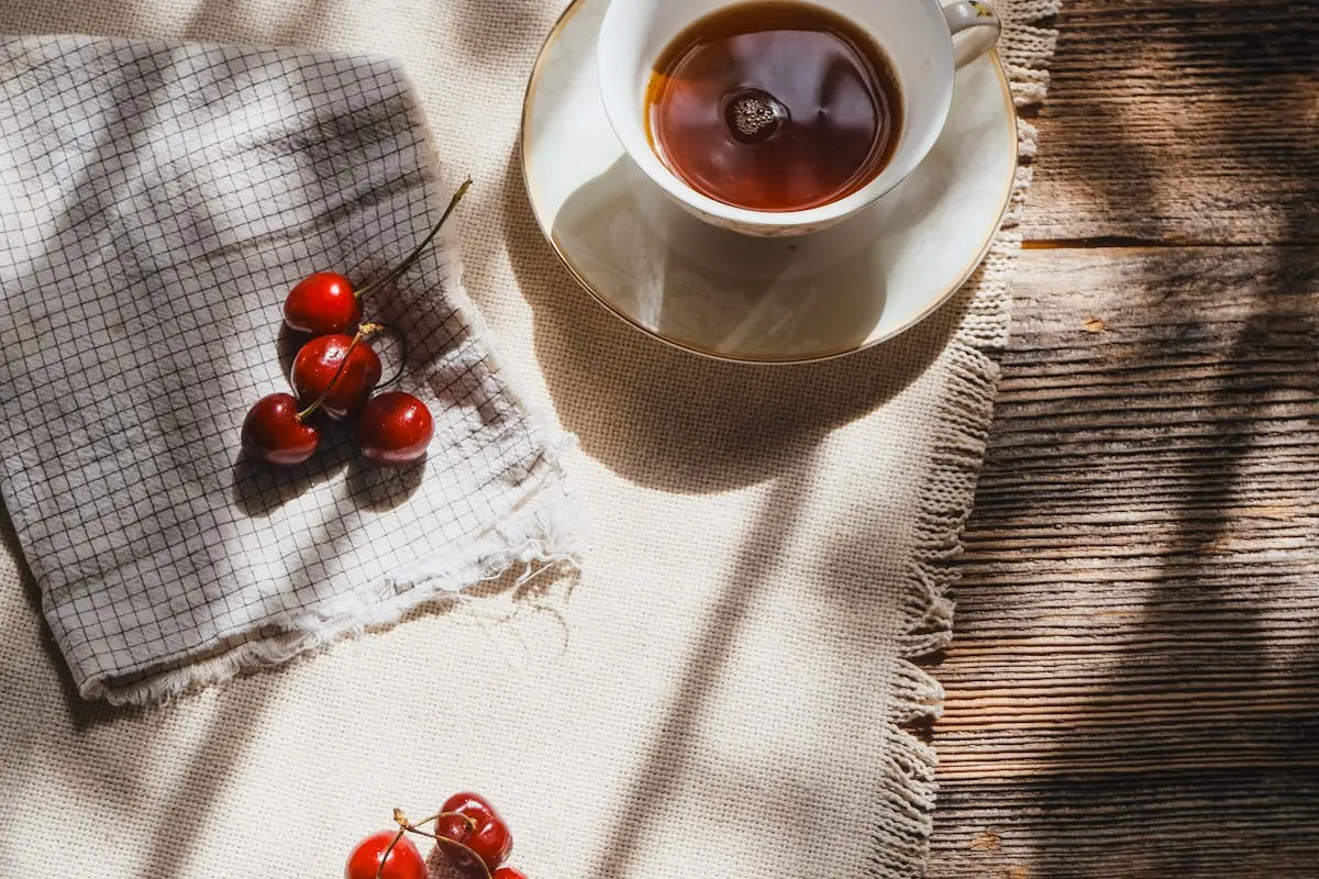 A cup of tea and cherries on a table