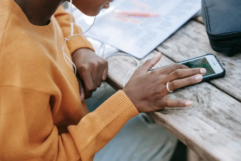 Black woman touching screen of smartphone at table