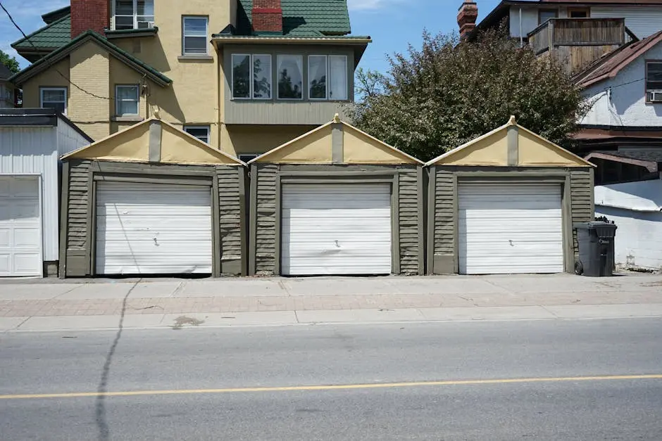 Row of three traditional residential garages with unique roof design on a sunny day.