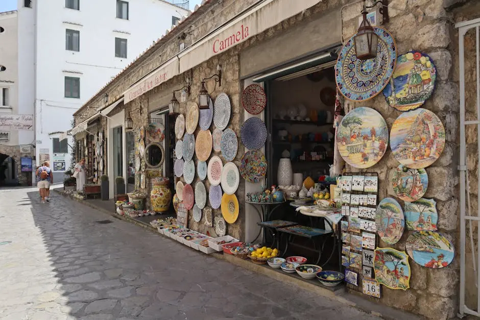 Charming ceramic art shop on a cobblestone street selling colorful souvenirs and plates in a picturesque town.